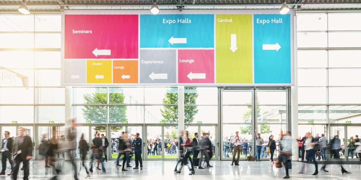 Crowd of business people in conference room walking under large vinyl banner